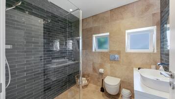 Une salle de bain moderne avec une douche à parois de verre, des toilettes et un lavabo.