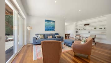 Un salon moderne avec un canapé bleu, deux fauteuils, une lampe sur pied et un tableau accroché au mur.