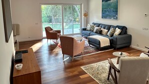 A modern living room with a sofa, armchairs, a coffee table, and a TV.
