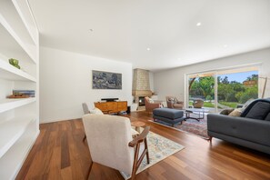 Un salon moderne avec un plancher en bois franc, une cheminée et une grande porte-fenêtre coulissante donnant sur l’extérieur.