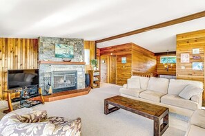 Uma sala de estar com lareira, televisão, sofá e mesa de centro.