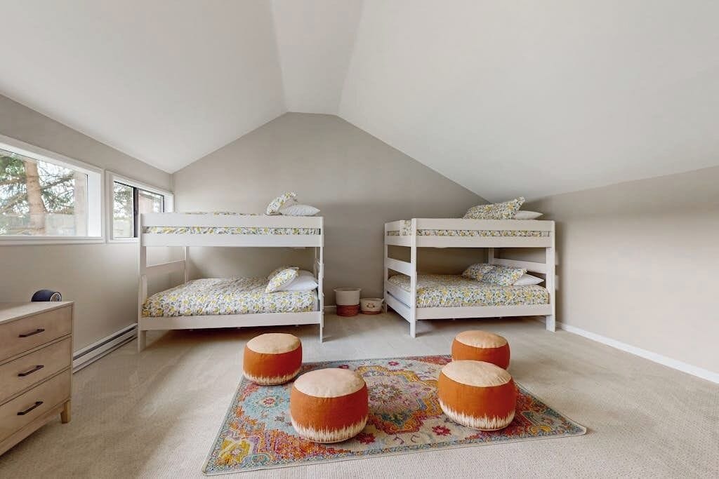 A room with two bunk beds, a small dresser, and a colorful rug.