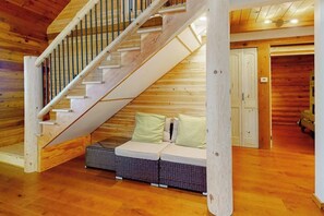 Eine Holztreppe führt zu einem Schlafzimmer mit Schlafgalerie, einem Sofa und einem kleinen Tisch.