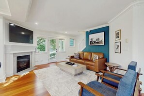 Ein Wohnzimmer mit Kamin, Fernseher, Sofa und Couchtisch.