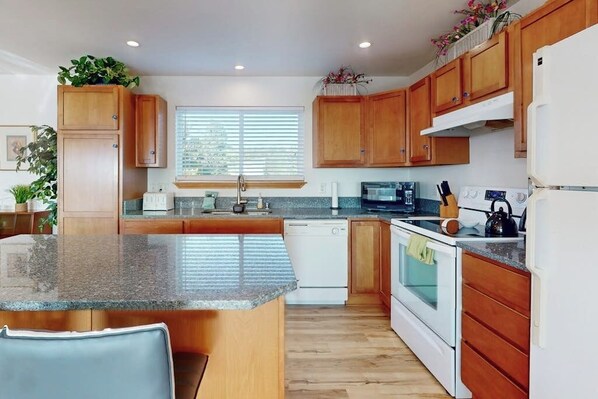 A kitchen with wooden cabinets, a granite countertop, a dishwasher, and a stove. - 2BR oceanview with spacious deck and wifi (Copalis Beach)