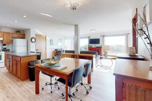 A modern kitchen with wooden cabinets, a dining area with a table and chairs, and a large window providing natural light. - 2BR oceanview with spacious deck and wifi (Copalis Beach)