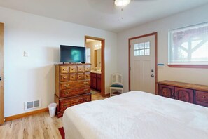 A bedroom with a bed, dresser, television, and a door leading to another room. - 2BR oceanview with spacious deck and wifi (Copalis Beach)