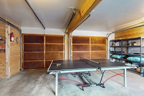 A ping pong table in a garage with wooden walls and metal shelving. - 4BR House with private beach, hot tub, & game room (Seabeck)