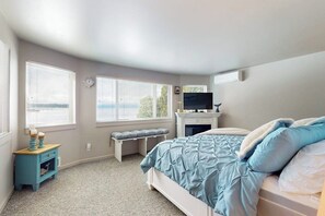 A bedroom with a bed, a bench, a fireplace, and a television. - 4BR House with private beach, hot tub, & game room (Seabeck)