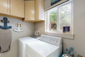 A laundry room with a washer and dryer, wooden cabinets, and decorative anchors on the wall. - 4BR House with private beach, hot tub, & game room (Seabeck)