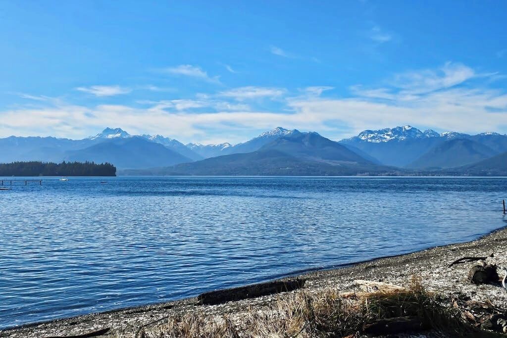 Un lac bordé de montagnes en arrière-plan et d’une rive rocheuse.