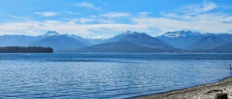A lake with mountains in the background and a rocky shoreline.