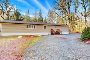 A single-story building with a gravel driveway and a wooden deck. - Secluded 3BR with hot tub, firepit & deck (Gold Bar)