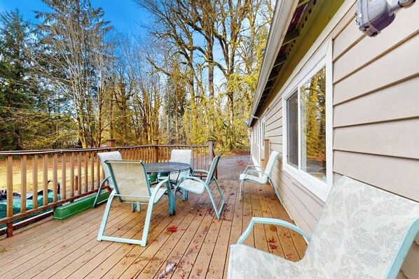 A deck with outdoor furniture, a railing, and a view of trees. - Secluded 3BR with hot tub, firepit & deck (Gold Bar)