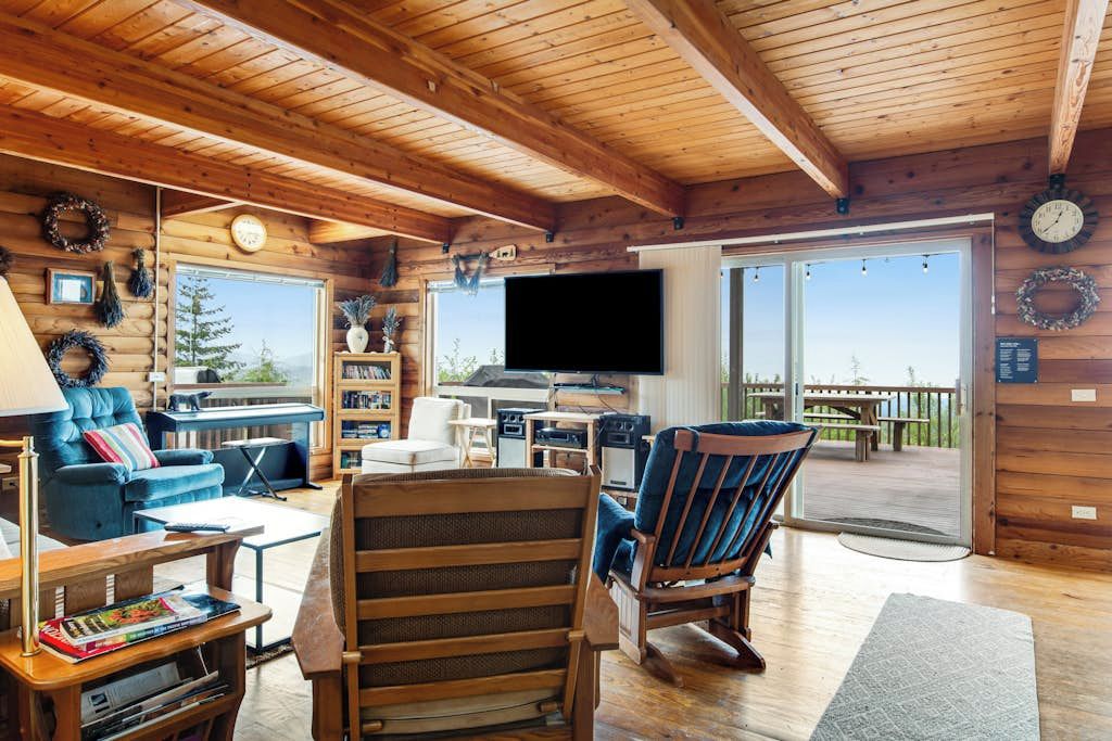 A cozy cabin interior with a wooden ceiling, a television, a fireplace, and a view of the outdoors.
