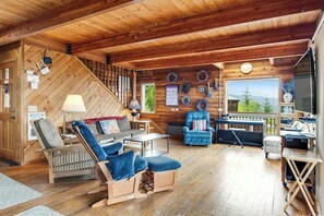 A wooden interior with a sofa, armchair, and a table, a staircase, and a view through a window. - Spacious 2BR Oceanview Dog Friendly - Hot Tub (Port Angeles)