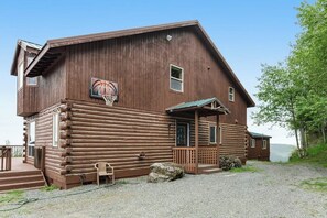 Eine Holzhütte mit einem Basketballkorb, einer Veranda und Blick auf die umliegende Landschaft.