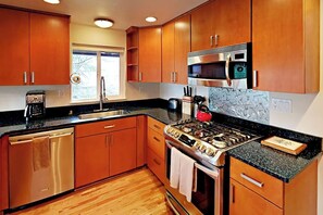A kitchen with wooden cabinets, a stainless steel stove, a microwave, and a dishwasher. - Modern 3BR Bayview - Elevator - Deck - Washer Dryer (Seattle)