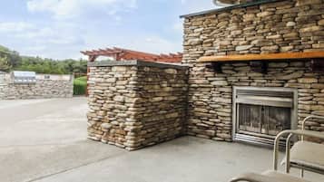 Eine Außenwand aus Stein mit Kamin, Sitzgelegenheit und einer Pergola.