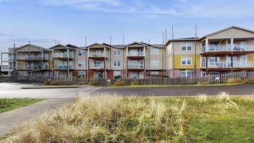 Una fila di edifici residenziali a più piani con balconi, un parcheggio e un'area verde in primo piano.