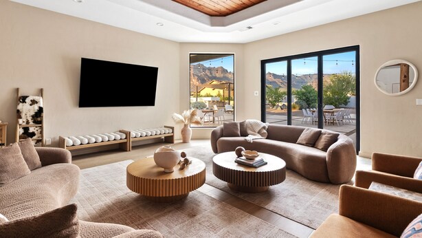 Una sala de estar moderna con un televisor de pantalla plana, asientos cómodos y vistas a montañas a través de amplios ventanales.