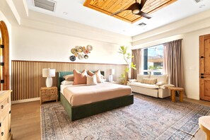 Quarto moderno com uma cama grande, um sofá, uma mesinha e um vaso de planta.