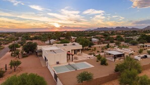 Zona residencial con un edificio grande que tiene cancha de tenis y asientos al aire libre.