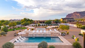 Una piscina con sillones de descanso, rodeada de jardines ajardinados y un telón de fondo montañoso.