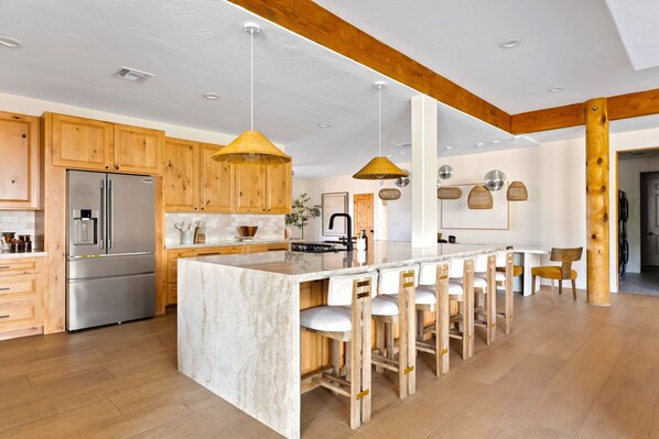 A spacious kitchen with wooden cabinets, a large island with bar stools, and pendant lighting. - Mountain Views: Heated Pool & Spa, Pickleball, Game Room, Private 1 Acre Oasis (Apache Junction)