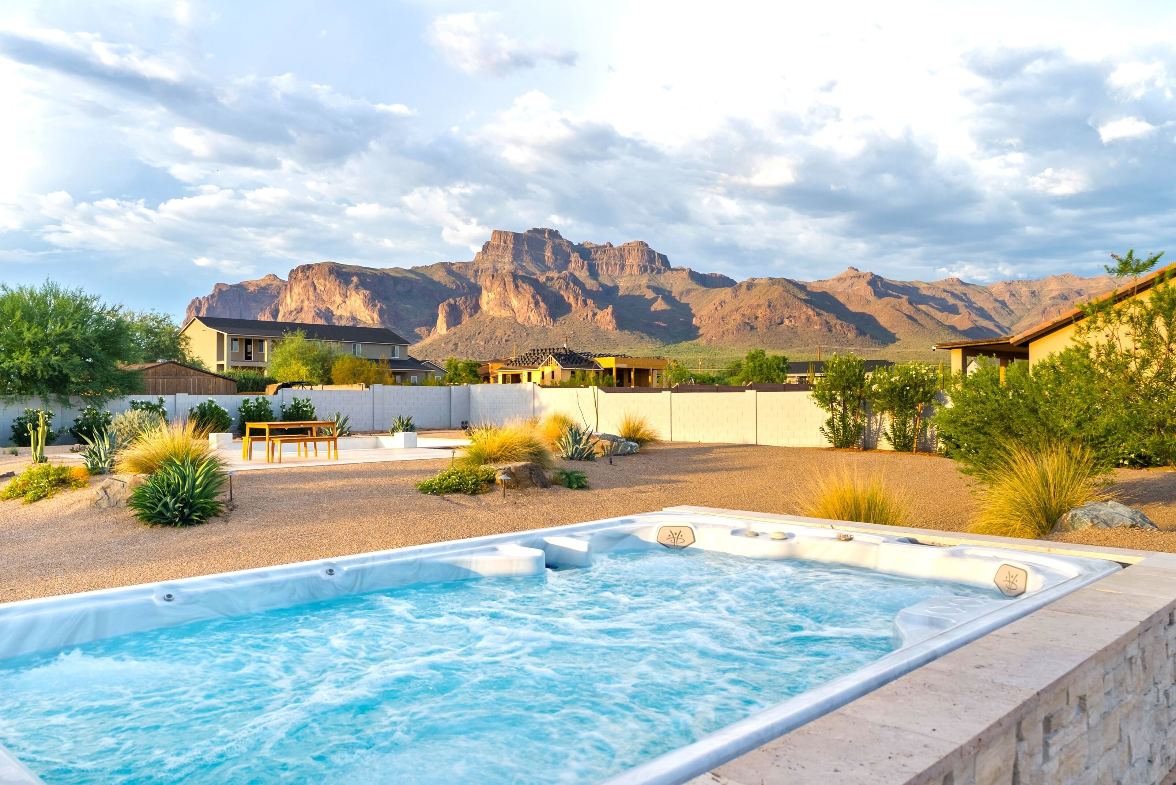 Un jacuzzi con vista a montañas, rodeado de un jardín ajardinado y edificios residenciales.
