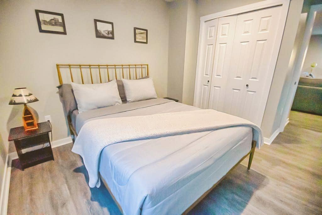 A bedroom with a bed, a nightstand, a lamp, and a wardrobe.