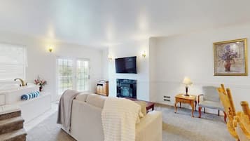 A living room with a sofa, a fireplace, a television, and a painting on the wall.
