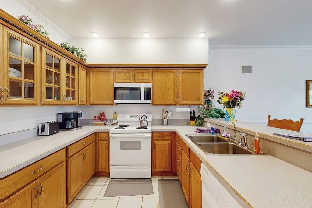 A kitchen with wooden cabinets, a microwave, a stove, and a sink.