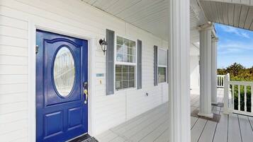 A white house with a blue front door, a covered porch, and a small front yard.
