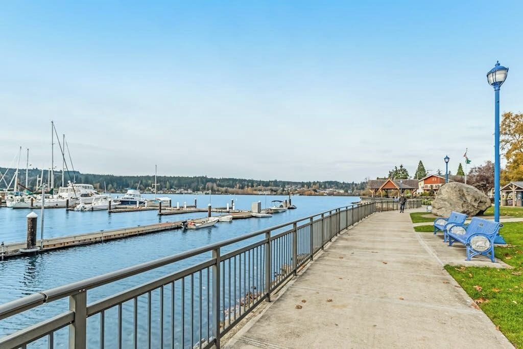 A waterfront promenade with a concrete walkway, benches, and a lamp post.