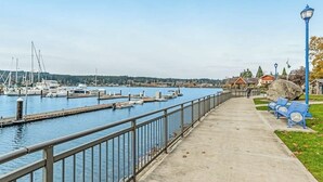 A waterfront promenade with a concrete walkway, benches, and a lamp post. - Front Street Suite Poulsbo (Poulsbo)
