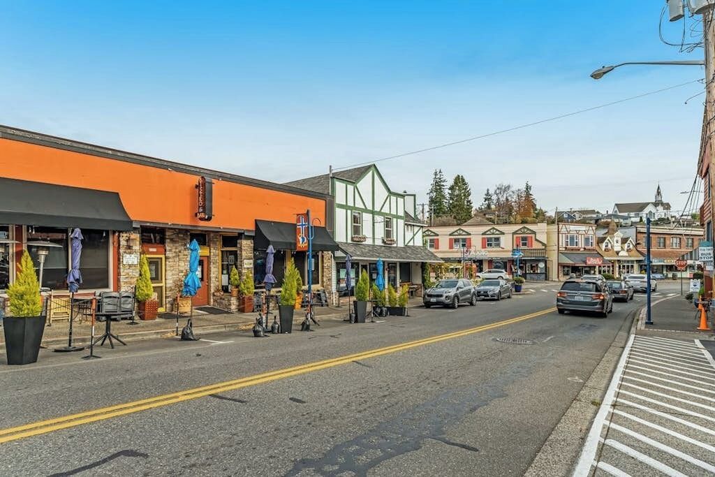 A street with buildings, a clear sky, and parked cars.