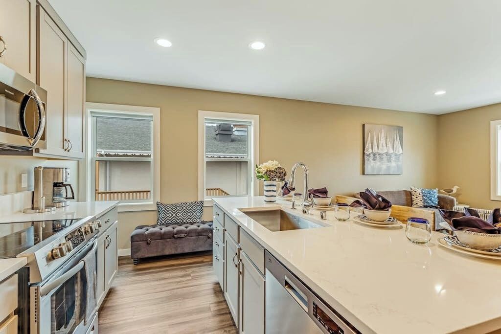 A modern kitchen with a large island, built-in appliances, and a seating area with a sofa and cushions.