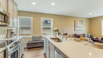 A modern kitchen with a large island, built-in appliances, and a seating area with a sofa and cushions.