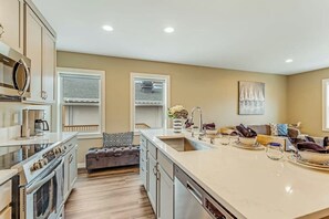 A modern kitchen with a large island, built-in appliances, and a seating area with a sofa and cushions.