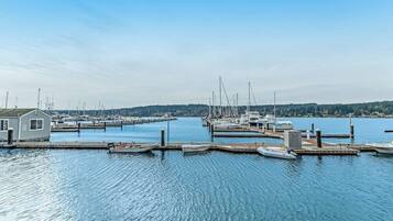 A marina with boats docked at piers, a small building, and calm water under a clear sky.