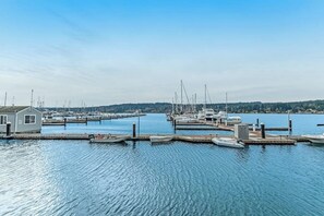 A marina with boats docked at piers, a small building, and calm water under a clear sky.