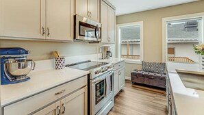 A kitchen with beige cabinets, a stainless steel oven, and a blue stand mixer. - Front Street Suite Poulsbo (Poulsbo)