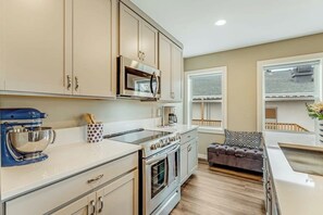 Una cocina con gabinetes color beige, un horno de acero inoxidable y una batidora de pie azul.