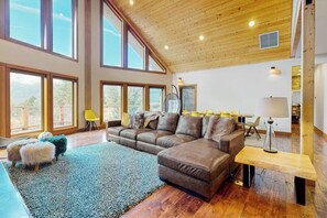 A spacious living room with a large sectional sofa, a small ottoman, and a wooden coffee table. - 4BR dog-friendly retreat with hot tub & deck views (Ronald)