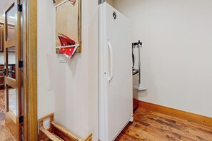 A room with a white refrigerator, wooden flooring, and a door leading to another room. - 4BR dog-friendly retreat with hot tub & deck views (Ronald)
