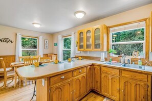 A kitchen with wooden cabinets, a large island, and a dining area with chairs.