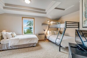 A bedroom with bunk beds, a window with a view, and a desk with a lamp. - Stunning waterfront 3BR with firepit & woodstove (Camano Island)
