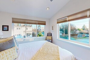 A bedroom with a large bed, two windows, and a view of the outside. - 2BR modern house, private backyard, fireplace, BBQ (Seattle)