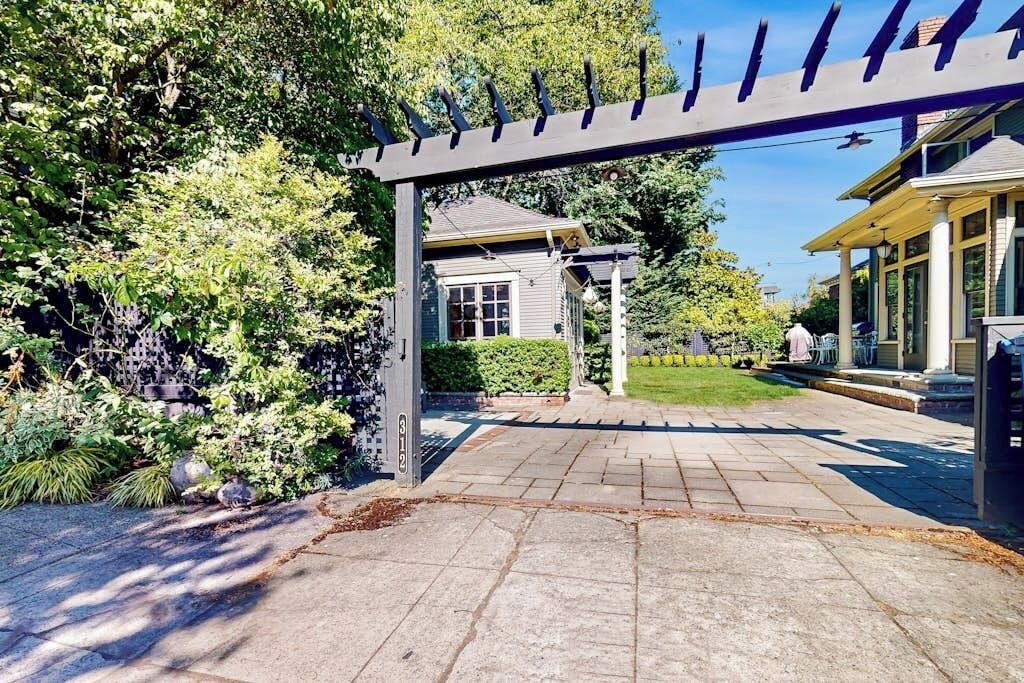 Una propiedad residencial con camino de entrada pavimentado, un porche cubierto y un jardín bien cuidado.